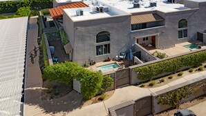 Un edificio moderno con piscina en la azotea, mobiliario exterior y un patio cubierto.