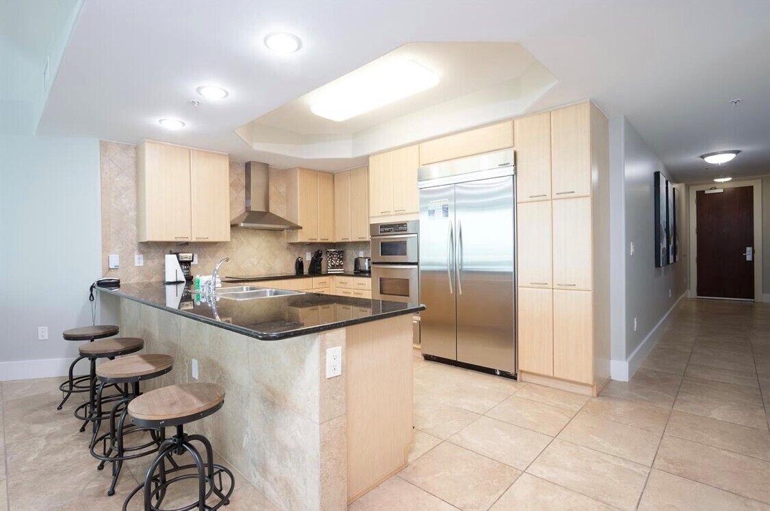 A modern kitchen with a central island, stainless steel appliances, and wooden cabinetry.