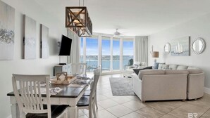 Un salon moderne avec un coin repas, de grandes fenêtres et une vue sur la mer.