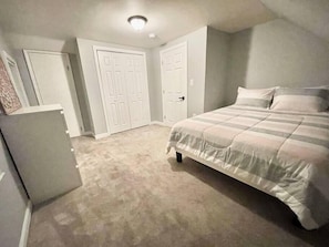 A bedroom with a bed, a dresser, and two doors. - Boston's Best Vacation Home (Boston)