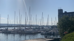 Una marina amb diversos velers amarrats, cel serena i un edifici al fons.