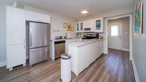 Een moderne keuken met witte kasten, roestvrijstalen apparatuur en een centraal eiland.