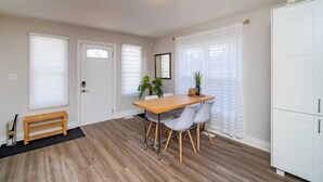 Een eetruimte met een houten tafel en stoelen, een bank en een witte kast.
