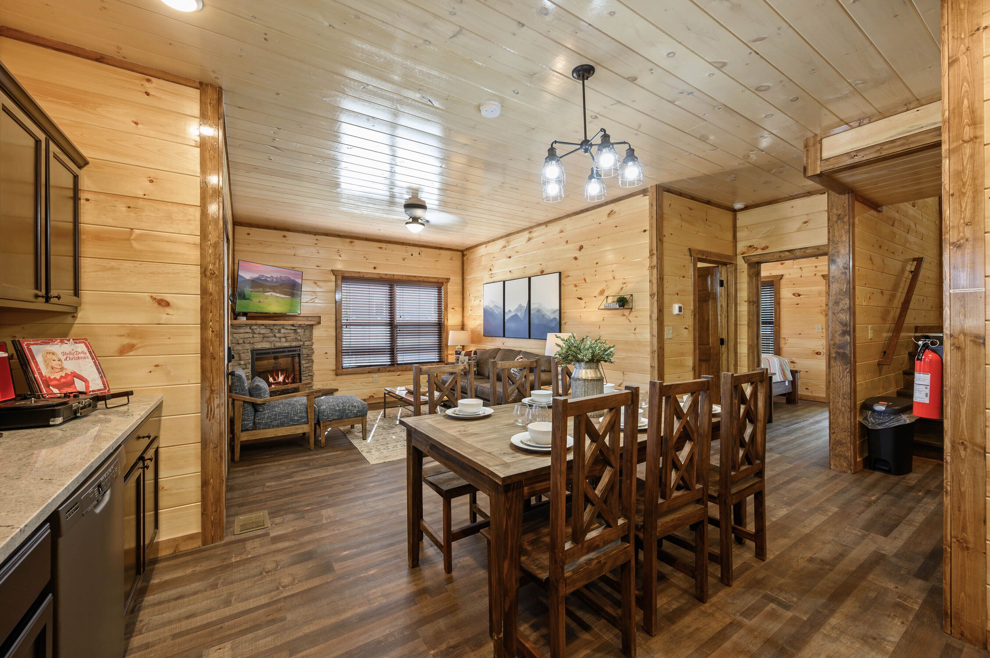 A wooden cabin interior with a dining area, kitchen, and living space.