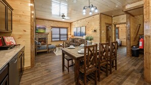 Interior d'una cabana de fusta amb menjador, cuina i zona d'estar.