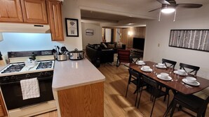A kitchen with a stove, oven, and dining area with a table set for four.