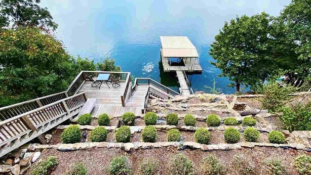 Una terrazza sul lago con struttura in legno, un sentiero in pietra e vista sul lago.