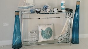 A room with a round mirror above a glass console table, decorated with nautical items and a sailboat model. - Tastefully decorated nautical Oasis in the Richmond Estate subdivision awaits yo (St. Ann Parish)
