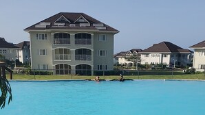 A large swimming pool with a view of multi-story residential buildings in the background. - Tastefully decorated nautical Oasis in the Richmond Estate subdivision awaits yo (St. Ann Parish)