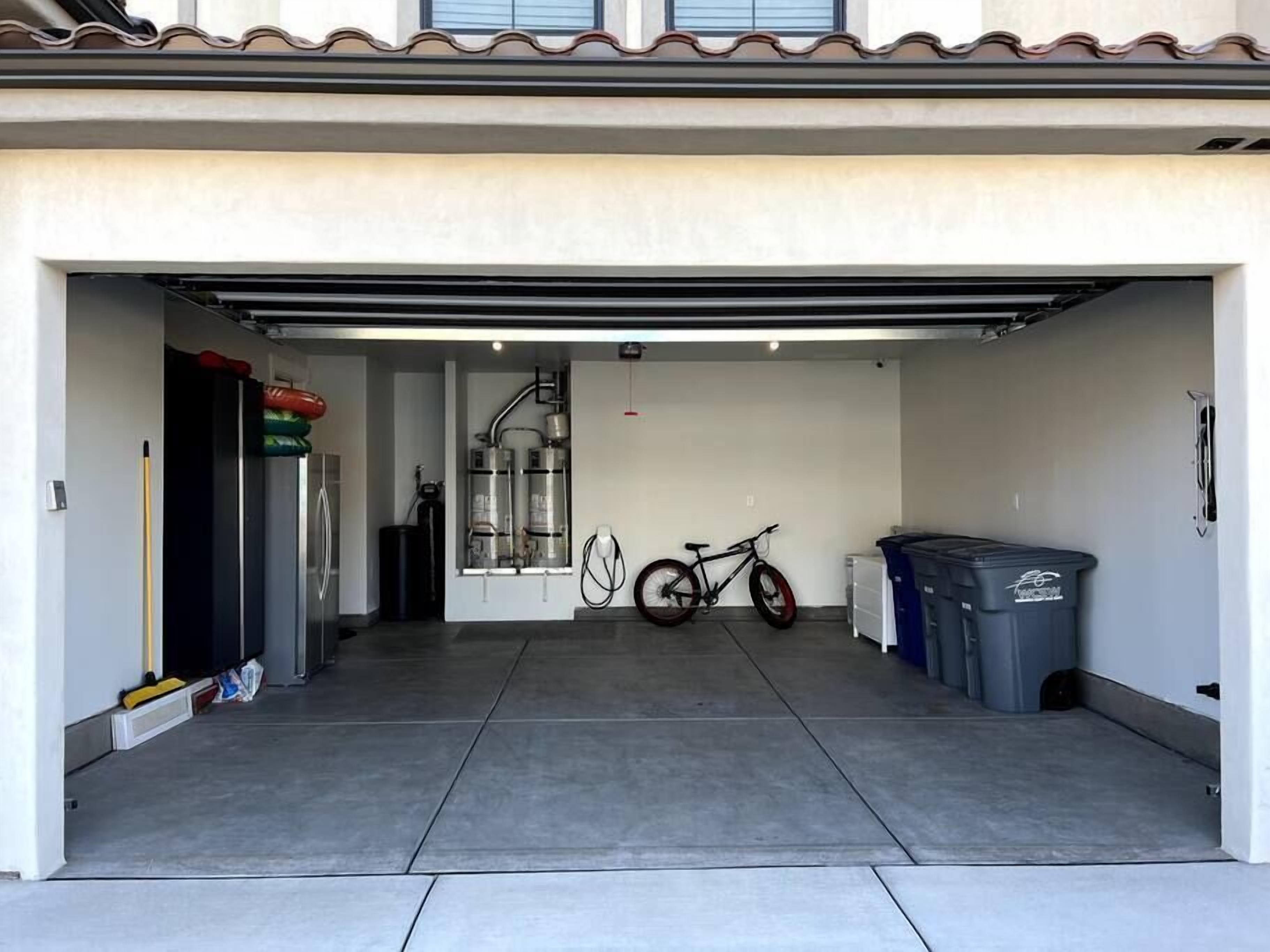 Een garage met een fiets, een afvalbak en een boiler.