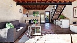 Een ruime woonkamer met een bank, salontafel en een trap naar een keuken.