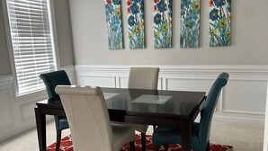 A dining room with a dark wooden table, four chairs, and a red patterned rug.