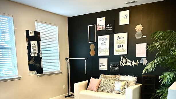 A room with a large black exercise mat, a white couch with patterned cushions, and motivational wall art.