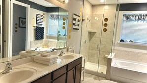 A modern bathroom with two sinks, a glass-enclosed shower, and a large mirror.