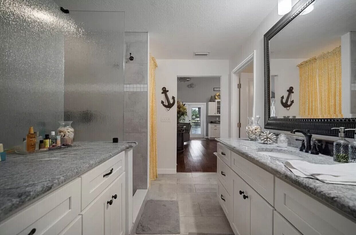 A modern bathroom with a large mirror, two sinks, and a shower area.