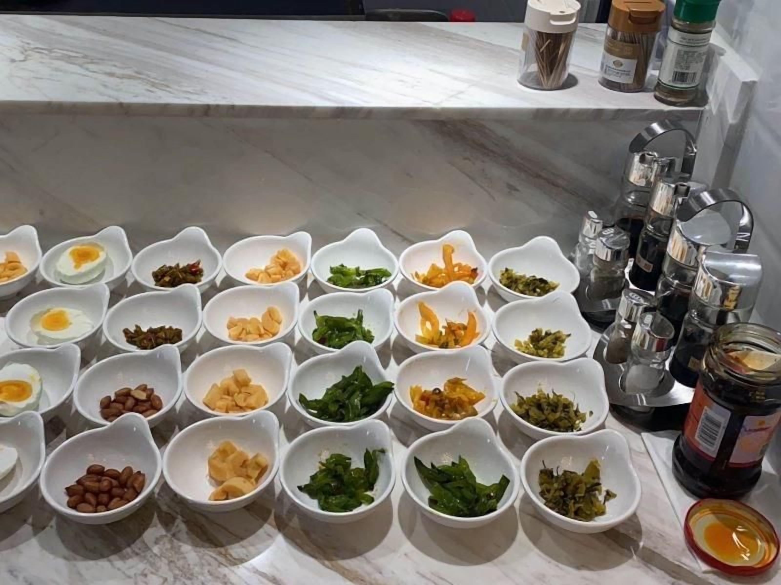 A kitchen counter with multiple small bowls containing various food ingredients.