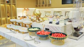 A buffet table with various food items and utensils, including bowls of fruit and a scale.