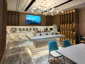 A modern hotel lobby with a marble floor, a central island with seating, a flat-screen TV, and a chandelier. - Greentree Eastern Hotel (Huai'an Suning Plaza Huaihai West Road) (Huai'an)