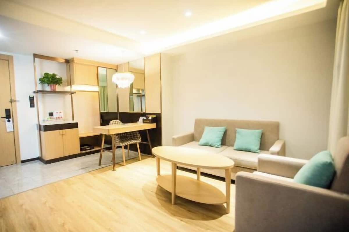 A modern living room with a sofa, a dining table, and a kitchen area with cabinets and a countertop.