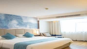 A hotel room with a large bed, a headboard with a decorative panel, a bedside table, and a window with curtains.