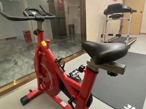 A red stationary bike in a room with a glass wall, a treadmill, and a mat on the floor. - Greentree Eastern Hotel (Huai'an Suning Plaza Huaihai West Road) (Huai'an)