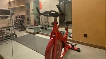 Uma academia com equipamentos de ginástica, incluindo uma bicicleta ergométrica, esteira e pesos.
