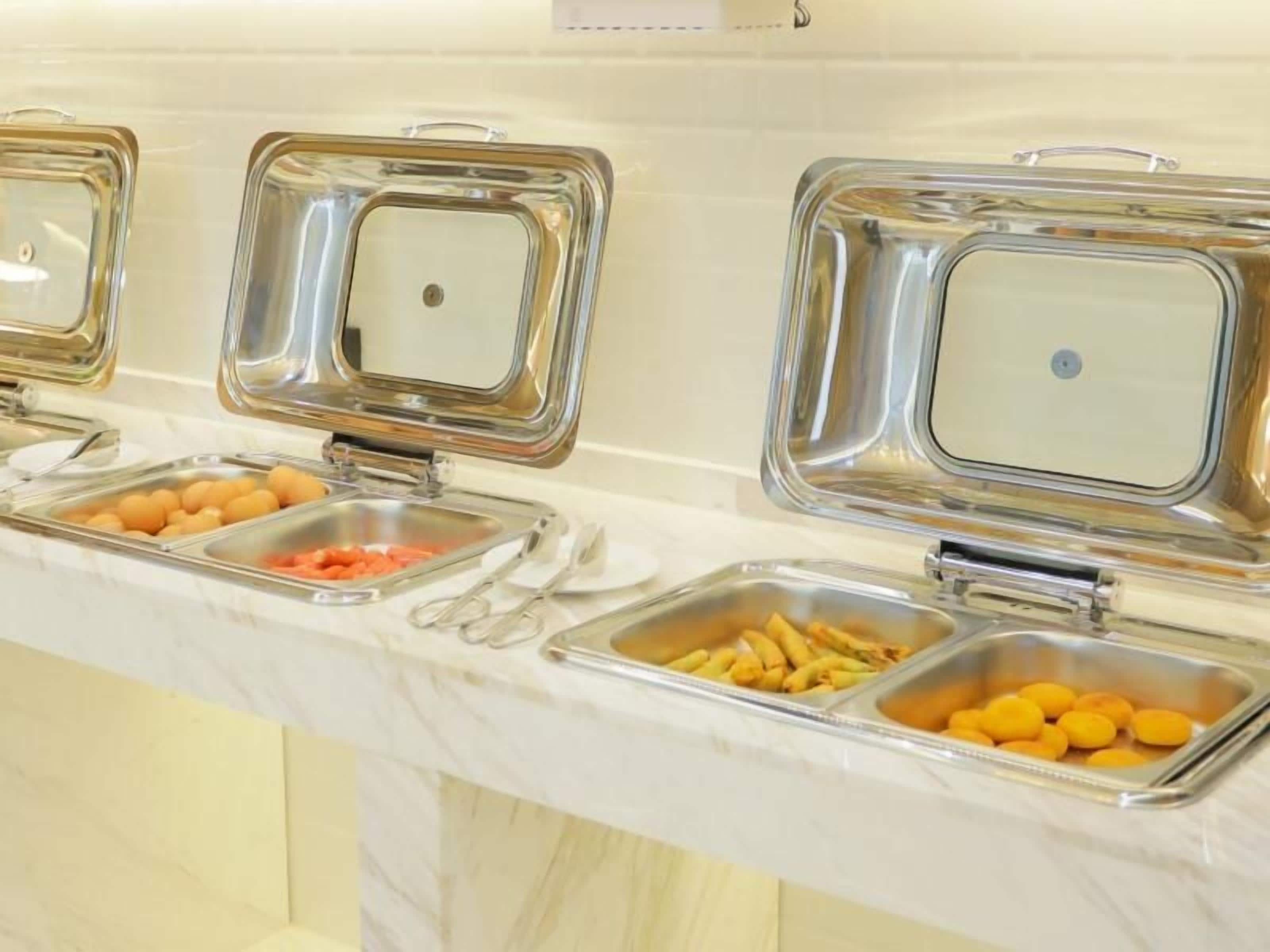 Ein Buffet mit mehreren Speisenstationen, jede mit einem Metalldeckel.