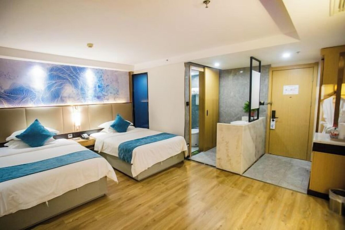A hotel room with two beds, a bathroom, and a large abstract painting on the wall.