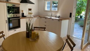 A modern kitchen with a central island, built-in oven, and a large window. - Gite Le Travezay avec piscine, sauna et Jacuzzi (Courcoué)