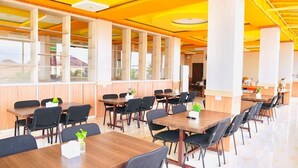 A spacious dining area with multiple tables and chairs, large windows, and a bright interior. - Hotel Amel Convention Hall (Banda Aceh)