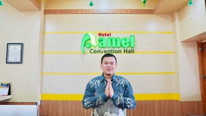 A man standing in front of a sign for Hotel Amel Convention Hall. - Hotel Amel Convention Hall (Banda Aceh)
