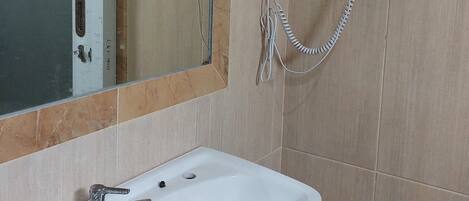 Un baño con un lavabo blanco, un espejo con marco de madera y un secador de pelo montado en la pared.