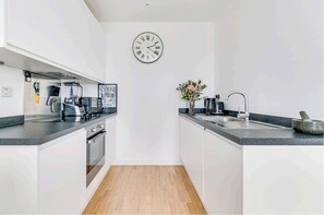 Fully equipped kitchen with a sink, coffee maker, toaster, and oven.