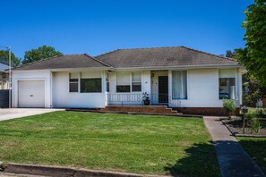 A single-story house with a front porch, a garage, and a well-maintained lawn. - Bancroft House Mudgee by Your Innkeeper (Mudgee)