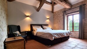 Ein Schlafzimmer mit einem hölzernen Bett, zwei Nachttischlampen, einem Sessel, einem Nachttisch und einem Fenster mit Vorhängen.