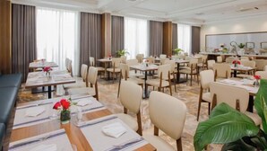 A hotel dining area with multiple tables, chairs, and a bar. - PHU THANG GRAND HOTEL (Duc Hoa Ha)