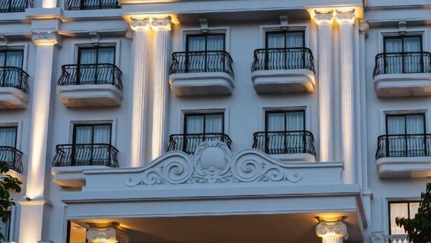 A multi-story building with balconies, columns, and a decorative entrance. - PHU THANG GRAND HOTEL (Duc Hoa Ha)