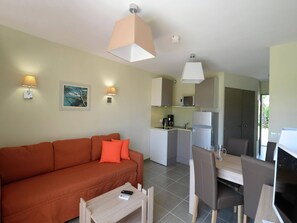A compact living space with a sofa, a dining table, chairs, a kitchen area with a microwave, and a refrigerator. - Romantic Vineyard Getaway (Sallèles-d'Aude)