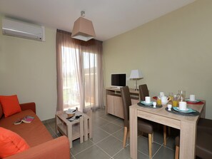 A hotel room with a sofa, a dining table with chairs, a TV, and a window with curtains. - Romantic Vineyard Getaway (Sallèles-d'Aude)