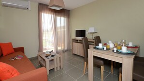 Ein Hotelzimmer mit Bett, Schreibtisch, Stuhl, Fernseher und Frühstückstisch.