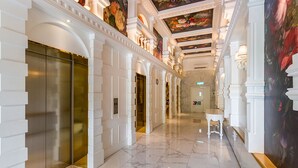 A hotel corridor with marble floors, white columns, and a mural on the right wall. - Arte Mont Kiara Managed by Airhost (Kuala Lumpur)