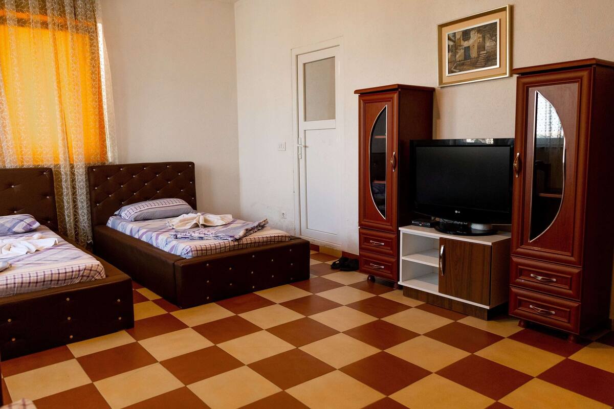 Une chambre avec deux lits, une télévision et une armoire.