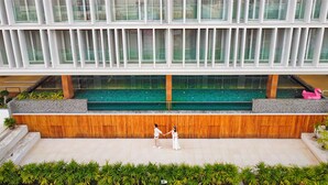 A modern building with a large glass facade, a central pool, and a wooden deck area. - Shambhala Hotel Pattaya (Pattaya)