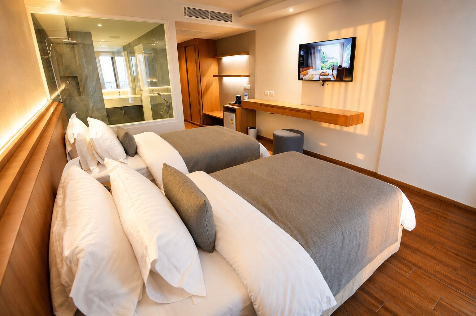A hotel room with two beds, a TV, a desk, and a bathroom.