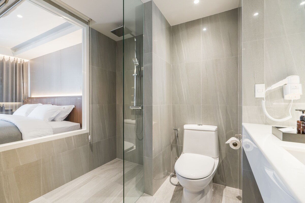 A modern bathroom with a glass-enclosed shower, a toilet, and a sink with a mirror.