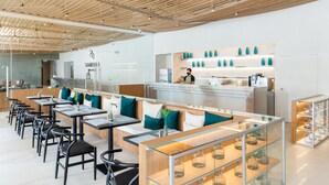 A modern restaurant with a long counter, seating area, and a display of blue vases. - Shambhala Hotel Pattaya (Pattaya)