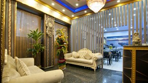 Een luxe lobby met een zachte bank, een decoratieve plant en een grote spiegel.