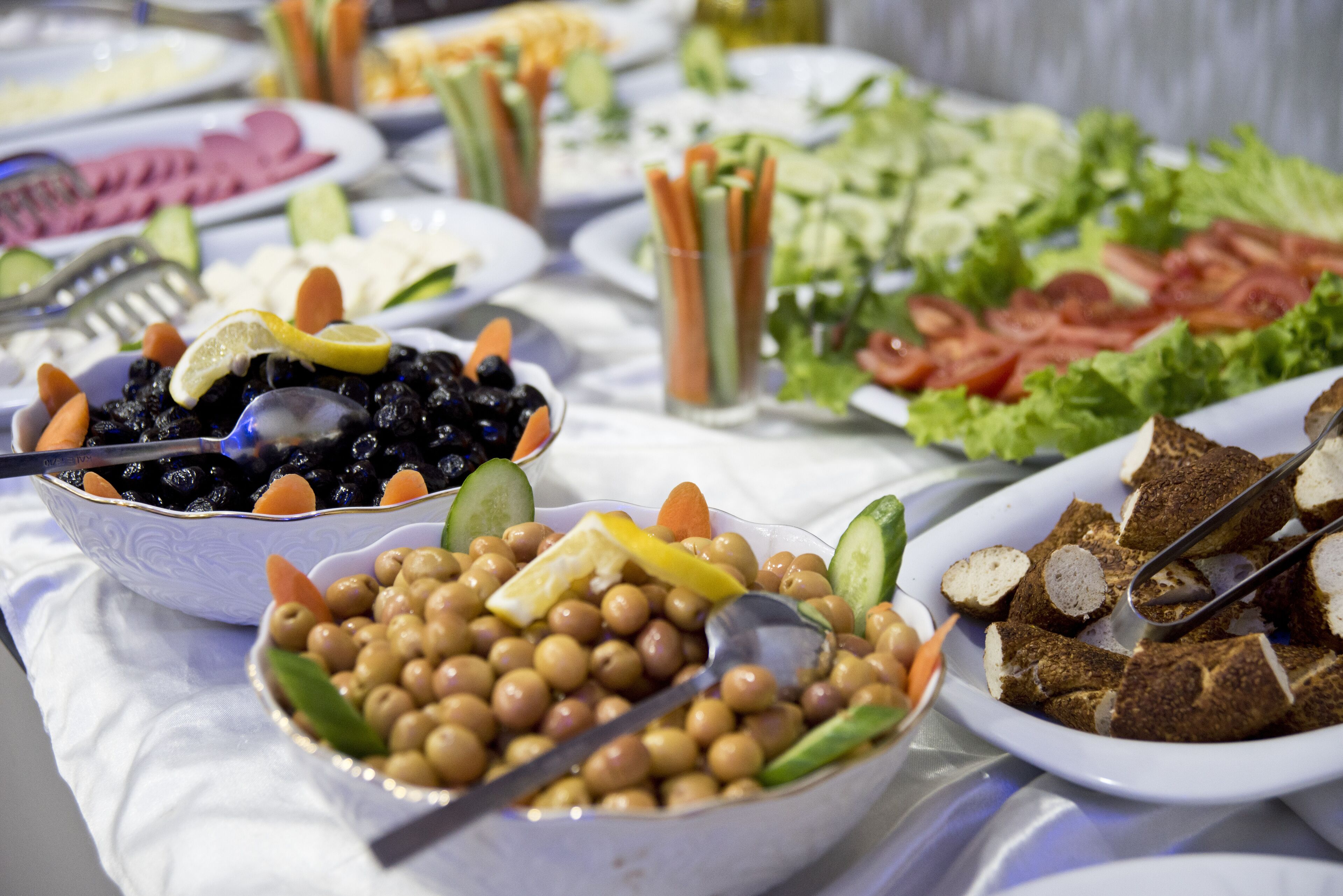 A buffet with various dishes including olives, chickpeas, and sliced vegetables.