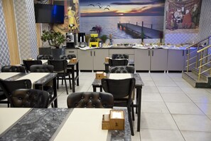 A restaurant with a view of the sea, featuring tables and chairs, a counter with food, and a TV mounted on the wall. - Golden Horn Park Hotel (Istanbul)