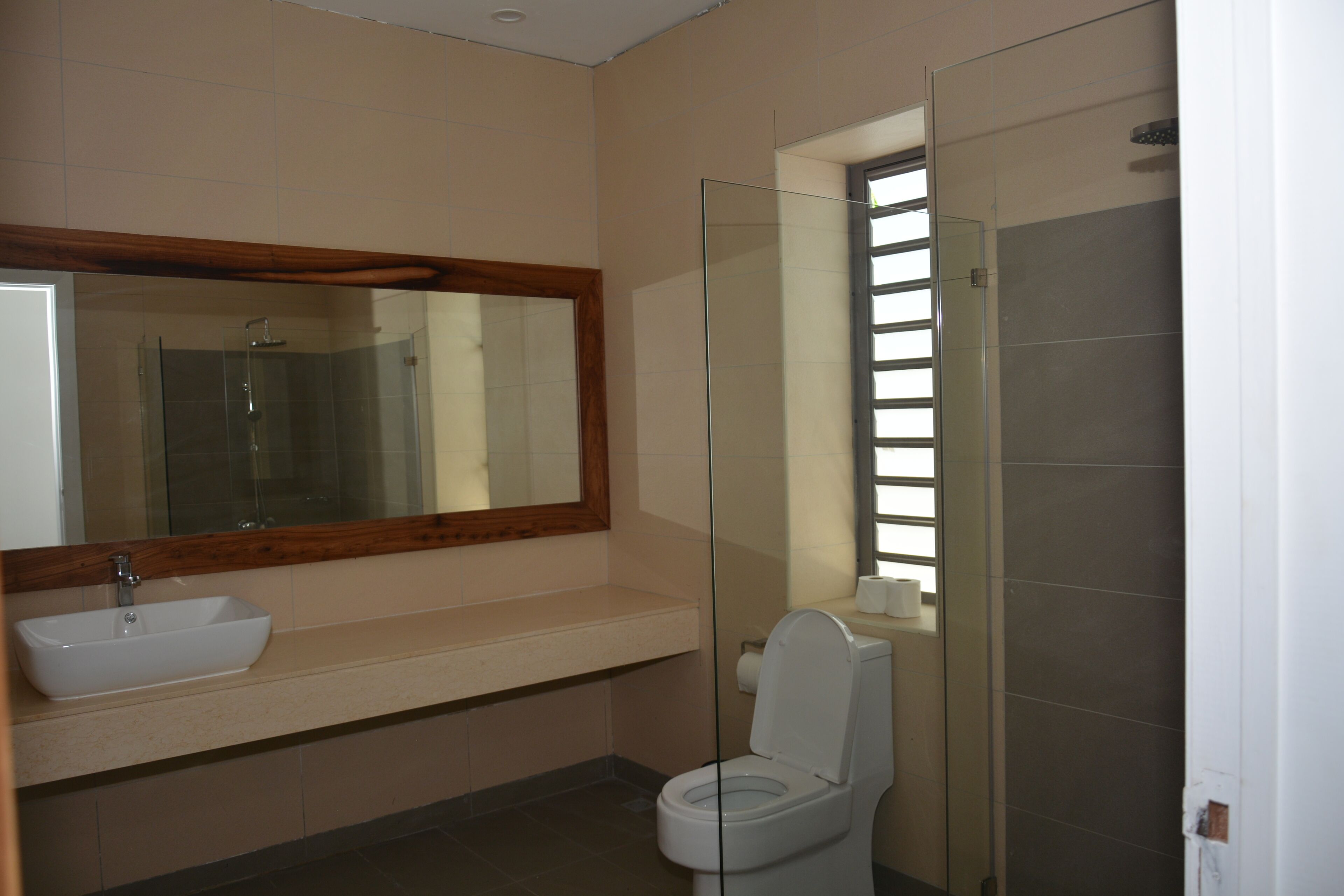 Een badkamer met een wastafel, spiegel, toilet en douchecabine met glazen wanden.